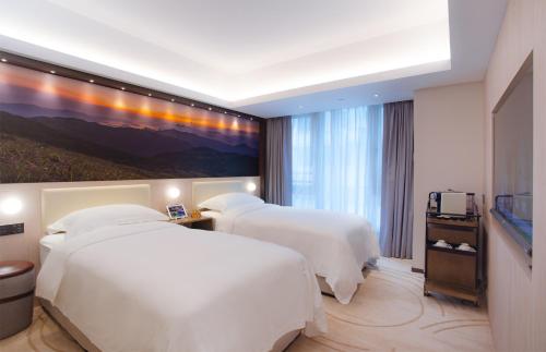 a hotel room with two beds and a painting on the wall at OASIS AVENUE - A GDH HOTEL in Hong Kong