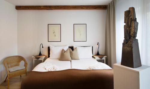 a bedroom with a large white bed and a chair at Gasthof Badl - Bed & Breakfast in Hall in Tirol