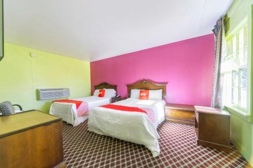 a room with two beds and a pink wall at OYO Hotel Brookhaven MS Hwy 51 North in Brookhaven