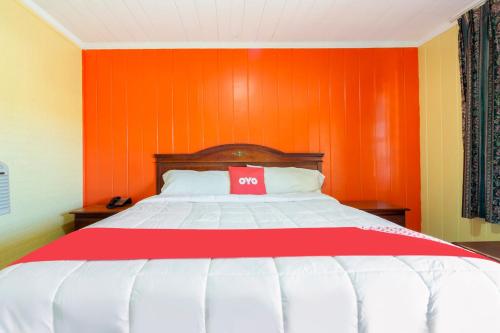 a bed in a room with an orange wall at OYO Hotel Brookhaven MS Hwy 51 North in Brookhaven