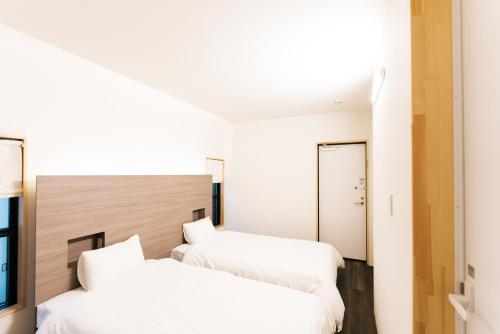 two beds in a room with white walls at B&B MIKAWA Info Centre - Kanazawa Fish Harbour in Kanazawa
