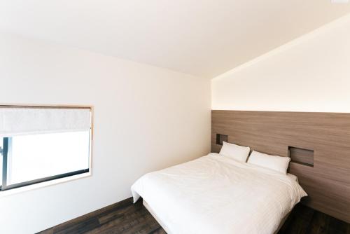 a bedroom with a white bed and a window at B&B MIKAWA Info Centre - Kanazawa Fish Harbour in Kanazawa