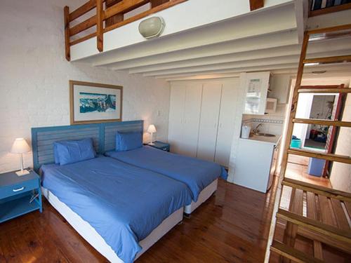 a bedroom with a blue bed and a loft bed at Friday Island in Langebaan