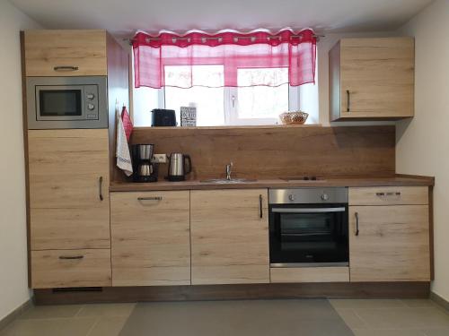 eine Küche mit Holzschränken, einem Waschbecken und einem Fenster in der Unterkunft wohnung-nummer-2 in Pielenhofen