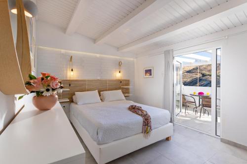 a white bedroom with a bed and a balcony at Castello Apartments in Panormos Rethymno
