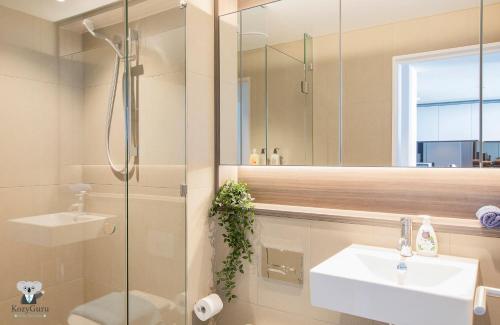 y baño con ducha, lavabo y espejo. en KOZYGURU DOCKLANDS LUXURY WATER VIEW APT 1 BED VDO915, en Melbourne