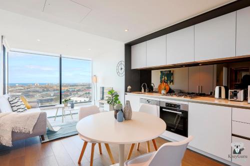 Una cocina y una sala de estar con mesa y sillas. en KOZYGURU DOCKLANDS LUXURY WATER VIEW APT 1 BED VDO915, en Melbourne