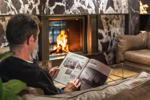 a woman sitting in front of a fire place reading a book at Hotel Arbaso in San Sebastián