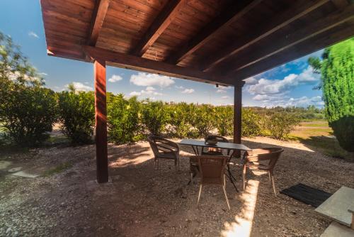 a table and chairs under a wooden pergola at Bonsai B&B Alghero in Santa Maria la Palma