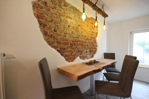een eetkamer met een bakstenen muur en een houten tafel bij Ferienwohnung Fischach in Fischach