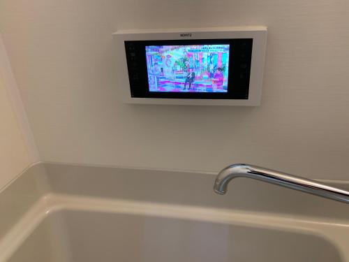 a television on a wall above a bath tub at One More Heart Kyoto Station South 4 in Nishi-kujō-Toriiguchichō
