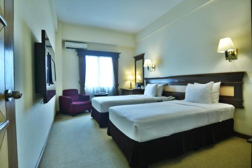 a hotel room with two beds and a window at Mega Anggrek Hotel Jakarta Slipi in Jakarta