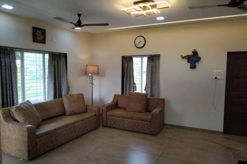 a living room with two couches and a clock on the wall at Spandan bunglow in Alibaug