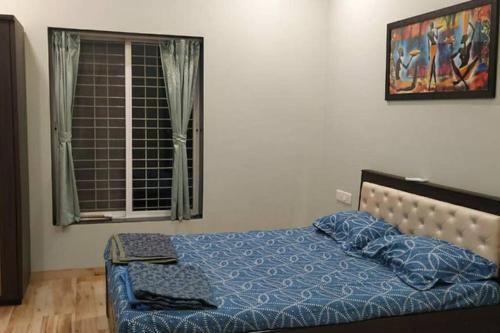 a bedroom with a bed with a blue comforter and a window at Spandan bunglow in Alibaug