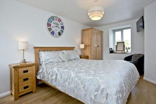 a bedroom with a bed and a clock on the wall at Anchor Cottage, Strete, Dartmouth in Strete