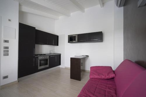 a living room with a purple couch and a kitchen at Le Terre di Maluk in Monte San Vito