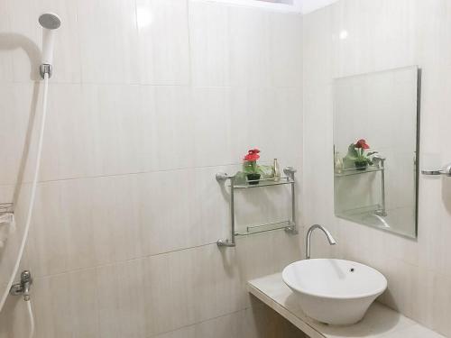 a white bathroom with a sink and a mirror at Rumah Panggung Guest House Syariah Mitra RedDoorz in Cirebon