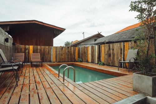 uma piscina no quintal com um deque de madeira e uma cerca em Nuan Boutique Hotel em Chiang Mai