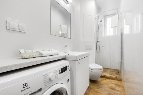 a white bathroom with a washing machine in it at Sunny Apartment Gdansk in Gdańsk