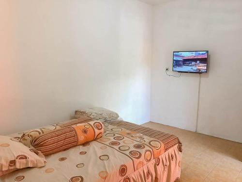 a bedroom with a bed and a tv on a wall at Rumah Panggung Guest House Syariah Mitra RedDoorz in Cirebon