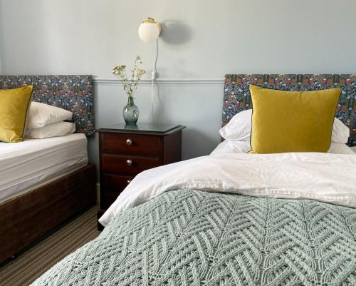 a bedroom with two beds with yellow pillows and a table at The Emsworth in Emsworth