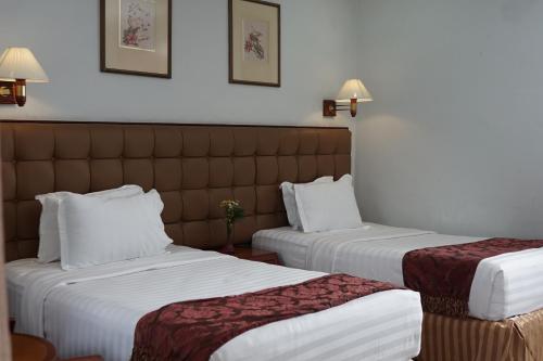 dwa łóżka w pokoju hotelowym z białymi prześcieradłami w obiekcie Rudang Hotel & Resort Berastagi w mieście Berastagi