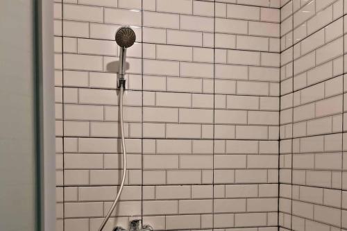 y baño de azulejos blancos con ducha y cabezal de ducha. en RedDoorz CBD Polonia Medan, en Medan