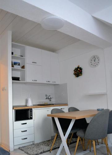 a kitchen with a table and chairs and a clock at Uni Kop in Brzeće