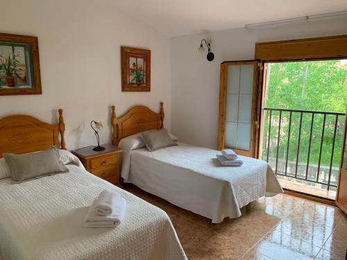 Casa Rural Arenal في Torrijo de la Cañada: غرفة نوم بسريرين ونافذة كبيرة