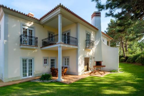 a white house with a lighthouse in the yard at Principes Townhouse in Casal da Lagoa Seca