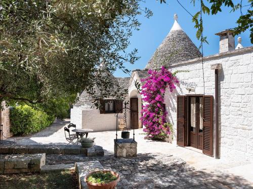 a house with flowers on the side of it at Trulli Uliveto Acquafonda in Alberobello