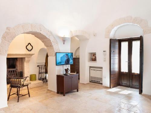 a living room with arches and a tv in a room at Trulli Uliveto Acquafonda in Alberobello