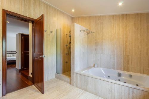 a bathroom with a tub and a walk in shower at Villa Les Oliveres Antonia By SunVillas Mallorca in El Port