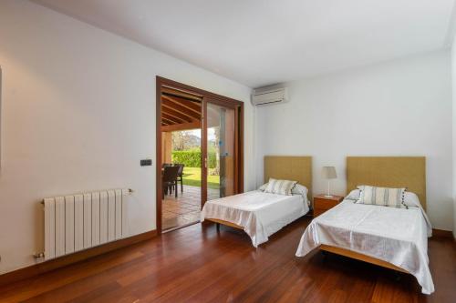 1 dormitorio con 2 camas y puerta corredera de cristal en Villa Les Oliveres Antonia By SunVillas Mallorca, en Port de Pollença (Puerto Pollensa)