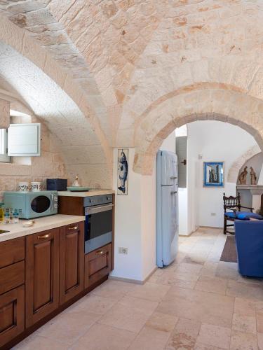 a kitchen with a white refrigerator and a stone ceiling at Trulli Uliveto Acquafonda in Alberobello