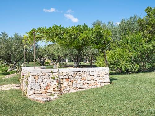 a stone wall in a field with trees in the background at Trulli Uliveto Acquafonda in Alberobello