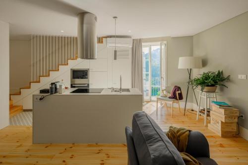 a living room with a kitchen and a staircase at Casa do Fontanário Stay in Amarante
