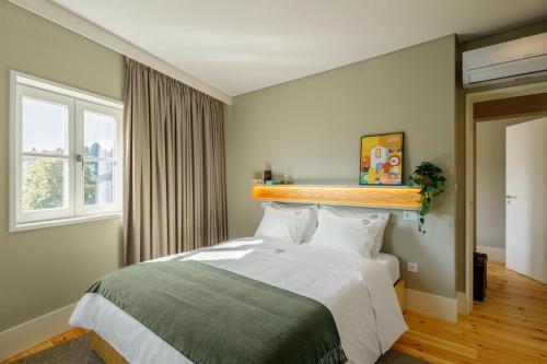 a bedroom with a large white bed and a window at Casa do Fontanário Stay in Amarante
