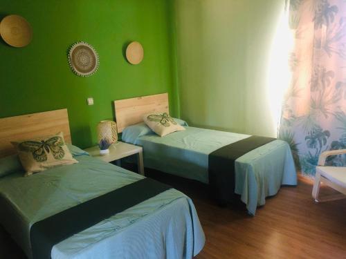 2 camas en una habitación con paredes verdes en Hospedería de Juan, en Fuentidueña de Tajo