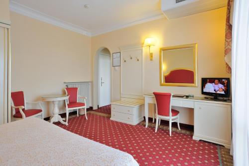 a hotel room with a bed and a desk and chairs at Palace Hotel Meggiorato in Abano Terme