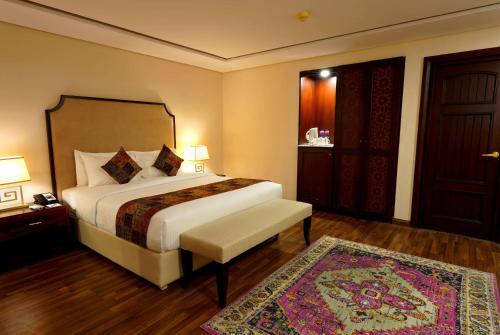 a bedroom with a large bed and a rug at Ramada by Wyndham Lahore Gulberg II in Lahore