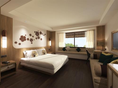 a bedroom with a bed and a couch and a window at Novotel Bogor Golf Resort in Bogor