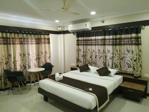 a bedroom with a bed and a table and chairs at Hotel Rose Mansion Manyata Tech Park in Bengaluru