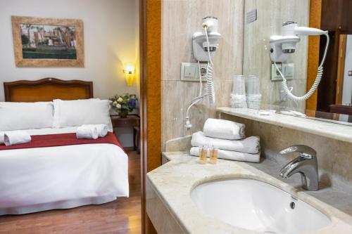 baño con lavabo y cama en Hotel Reina Cristina, en Granada