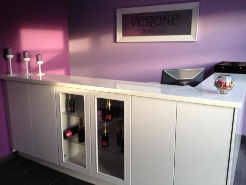 a white counter with bottles of wine in it at V E R O N E - Rooms & Suites - Liège - Rocourt in Liège