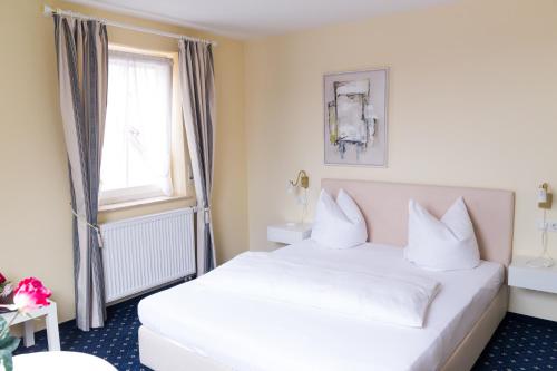 Neuffen的住宿－Hotel - Restaurant Traube，酒店客房设有白色的床和窗户。