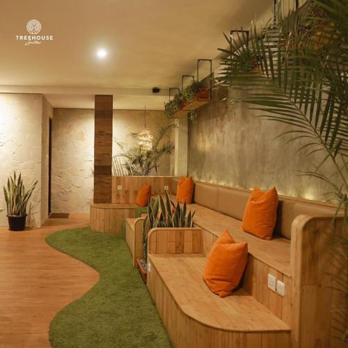 a lobby with a bench with orange pillows and plants at Treehouse Suites - Boutique Serviced Apartment in Jakarta
