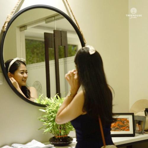 a woman brushing her hair in front of a mirror at Treehouse Suites - Boutique Serviced Apartment in Jakarta