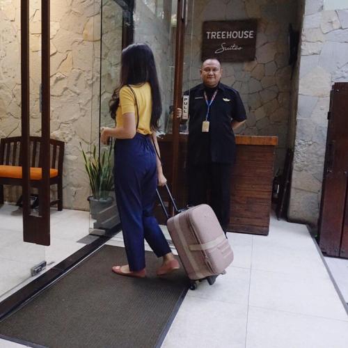 a woman walking into a hotel with her luggage at Treehouse Suites - Boutique Serviced Apartment in Jakarta