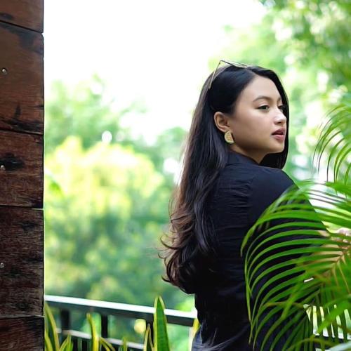 a woman with long hair standing next to a plant at Treehouse Suites - Boutique Serviced Apartment in Jakarta